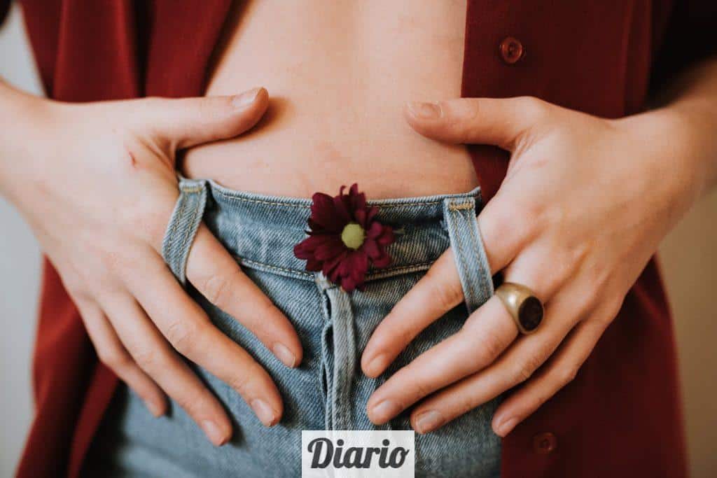Crop faceless female in casual clothes decorated with blooming flower revealing bare stomach