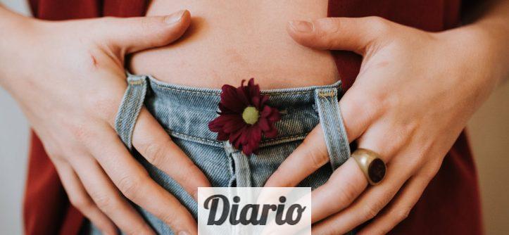 Crop faceless female in casual clothes decorated with blooming flower revealing bare stomach