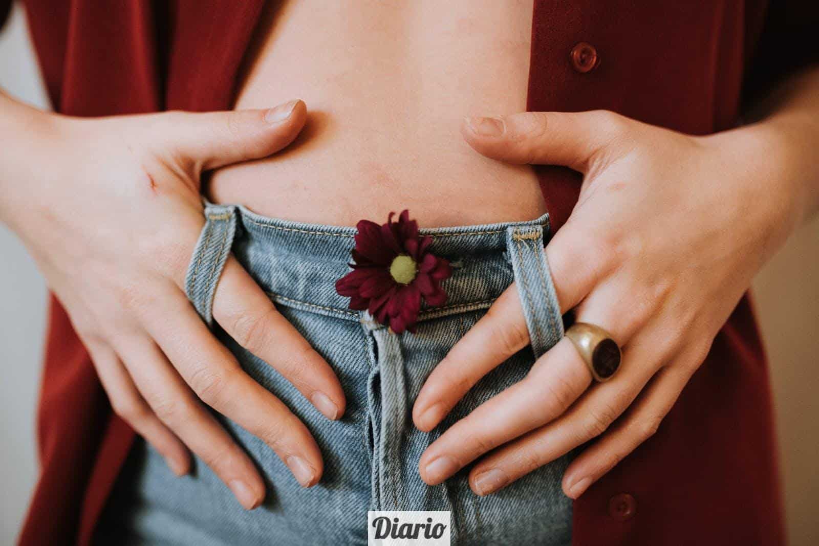 Crop faceless female in casual clothes decorated with blooming flower revealing bare stomach