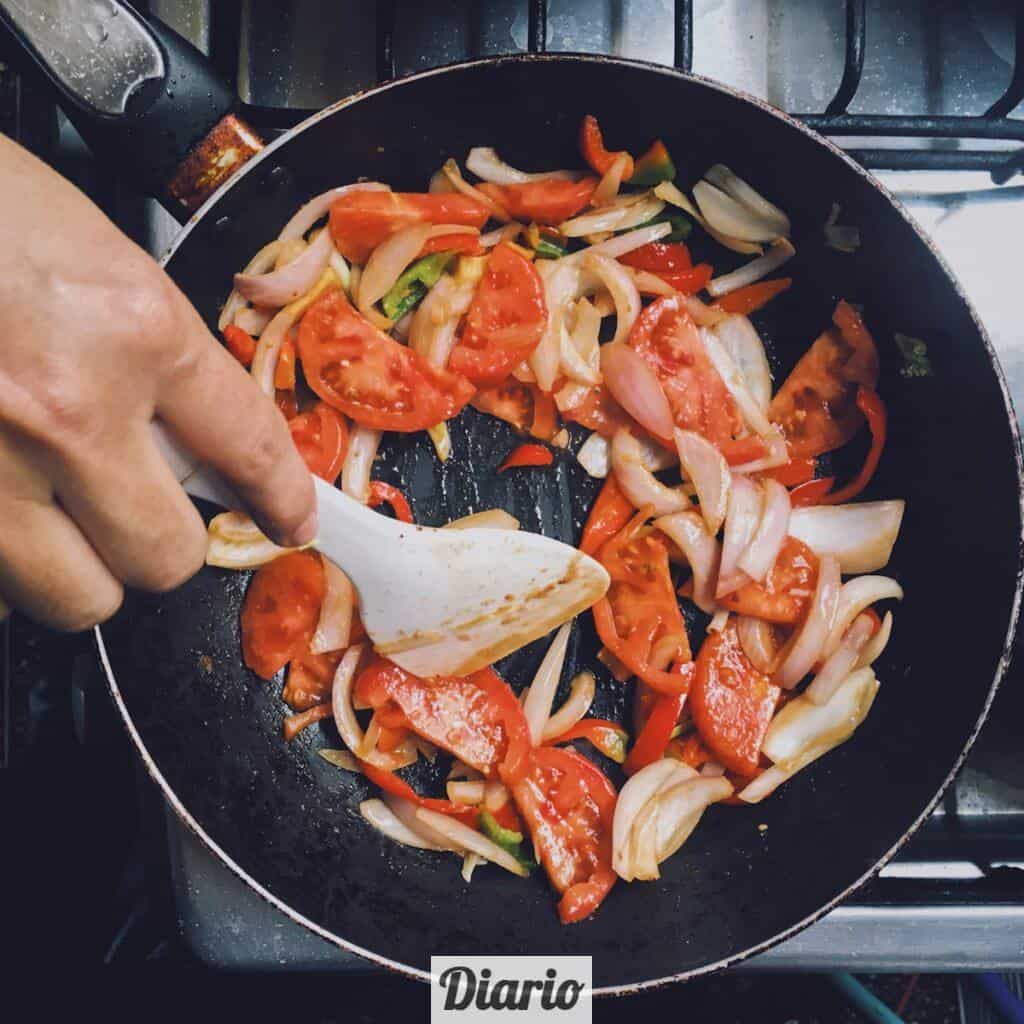person holding black frying pan with cooked food