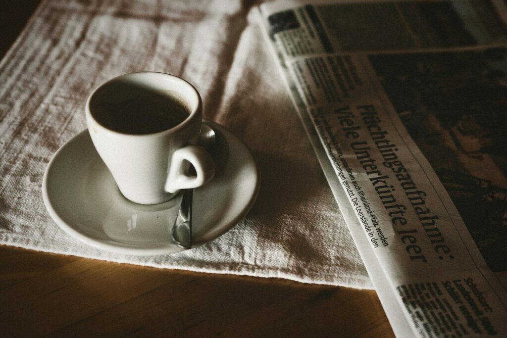 Periódico doblado junto a una taza de café por la mañana